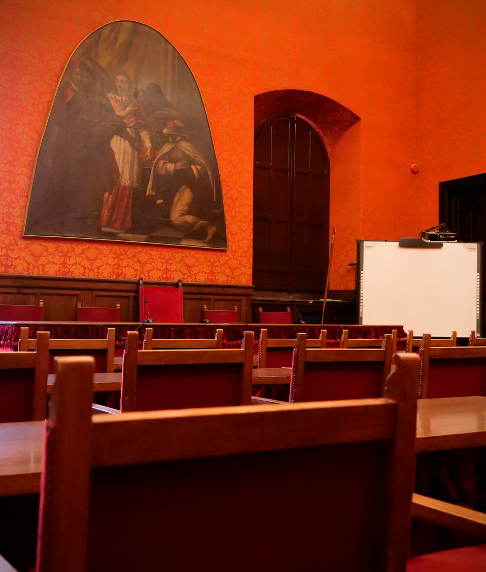 Sala de conferencias presidida por un gran cuadro en la Facultad de Derecho